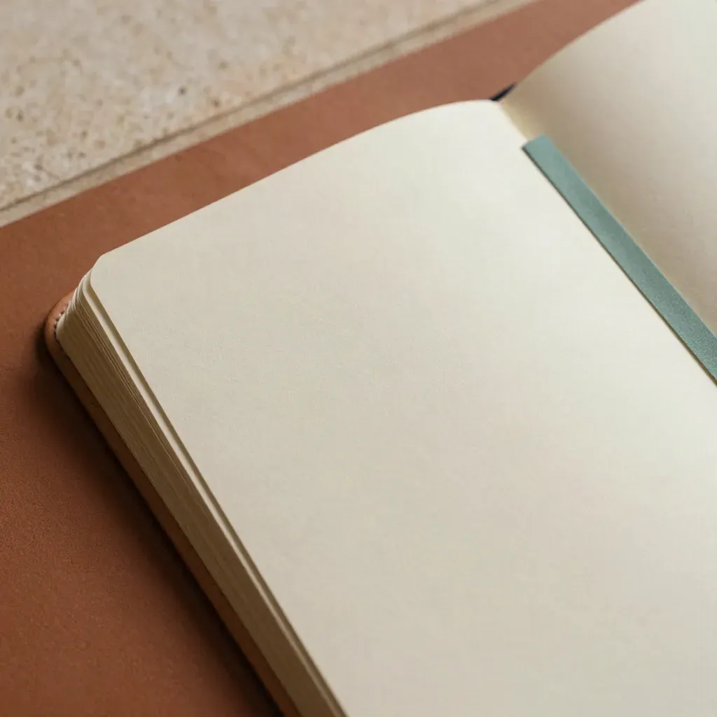 Macro top-down of a textured planner with swinging dividers and a teal accent on terracotta plaster.